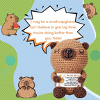 Crocheted capybara holding a card with text, surrounded by small capybaras and watermelon on a colorful background.