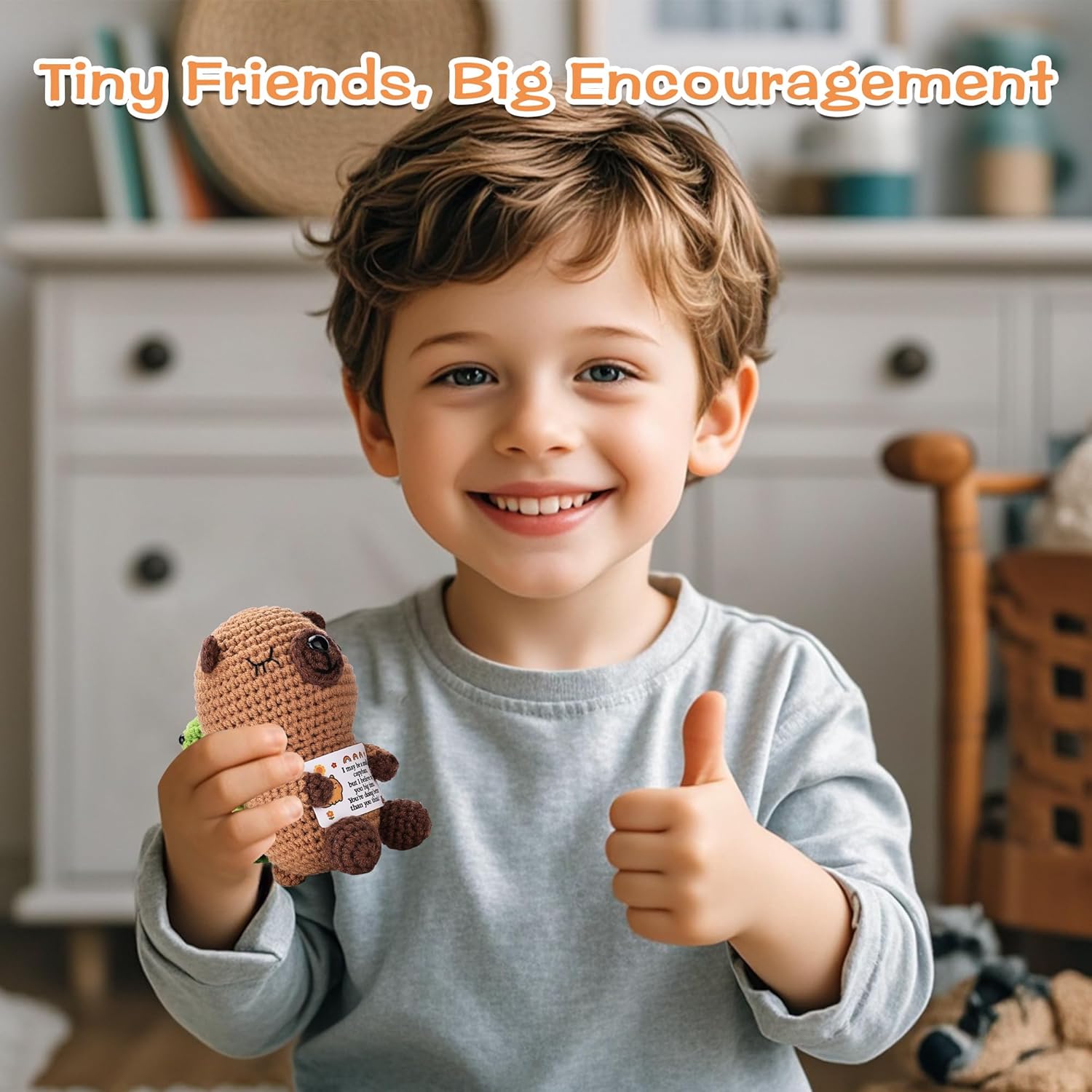 Child holding a small brown plush toy with a thumbs-up gesture, smiling.