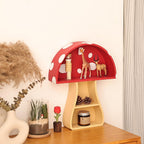 Red polka dot mushroom-shaped shelf with decorative items on a wooden surface.