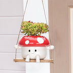 Mushroom-shaped hanging planter with succulents on a neutral background