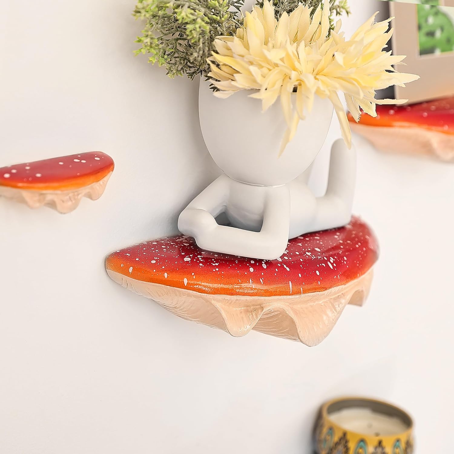 Decorative wall shelves with a sitting figure and plants on a white wall.