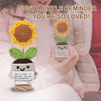 Person holding a crocheted sunflower plant with a message card, surrounded by text 'JUST A LITTLE REMINDER — YOU'RE SO LOVED!'.